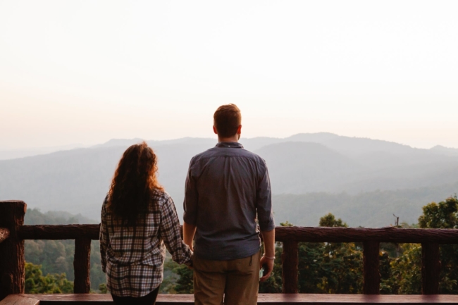 unrecognizable couple enjoying sunset over mountains during romantic trip