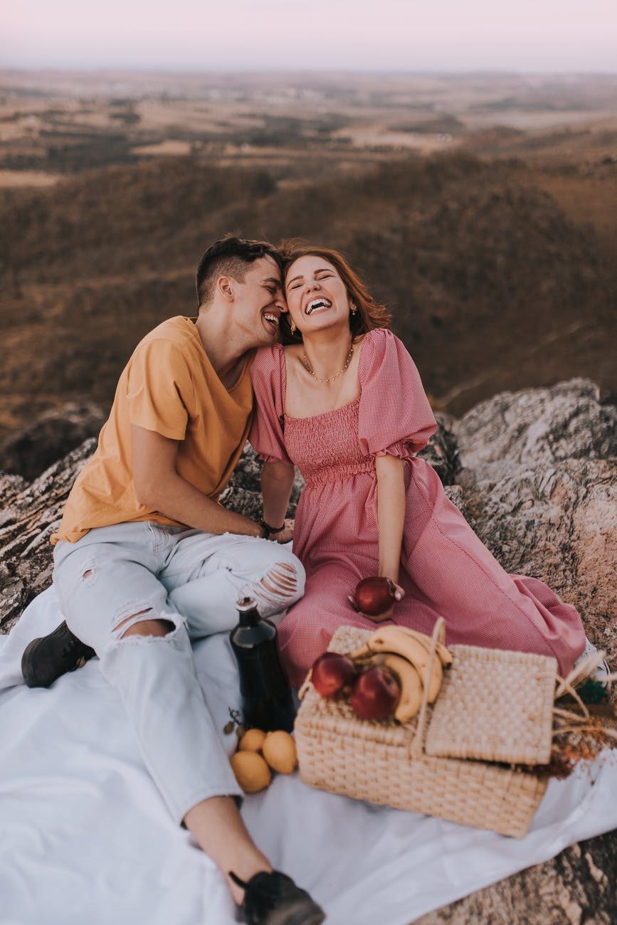 laughing couple with closed eyes near fresh fruits in mountains