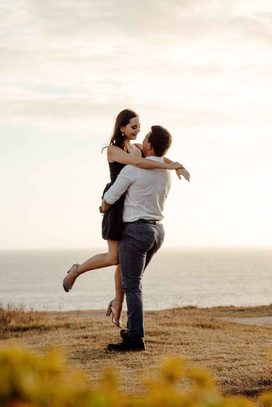 couple hugging on grassy coast near sea