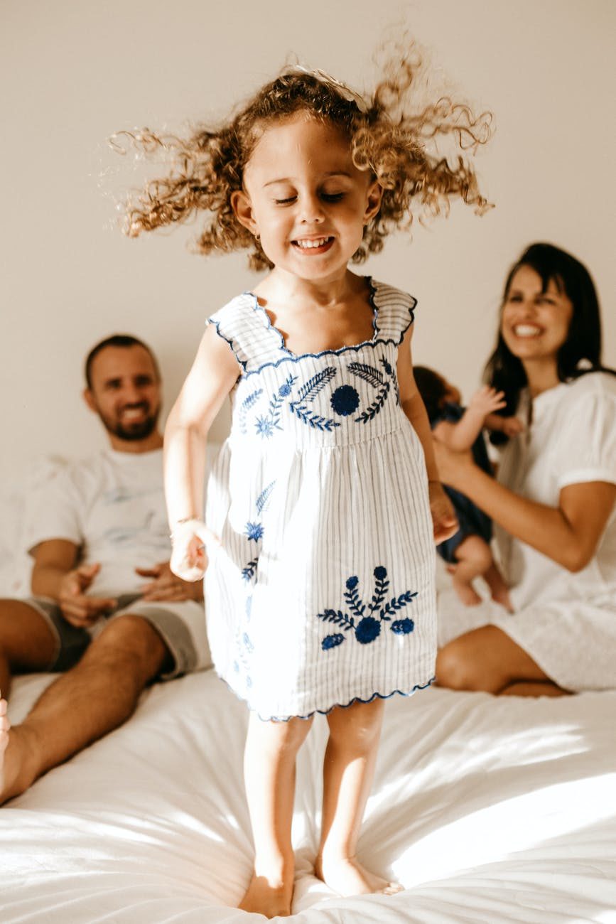 happy little kid having fun on bed with cheerful parents