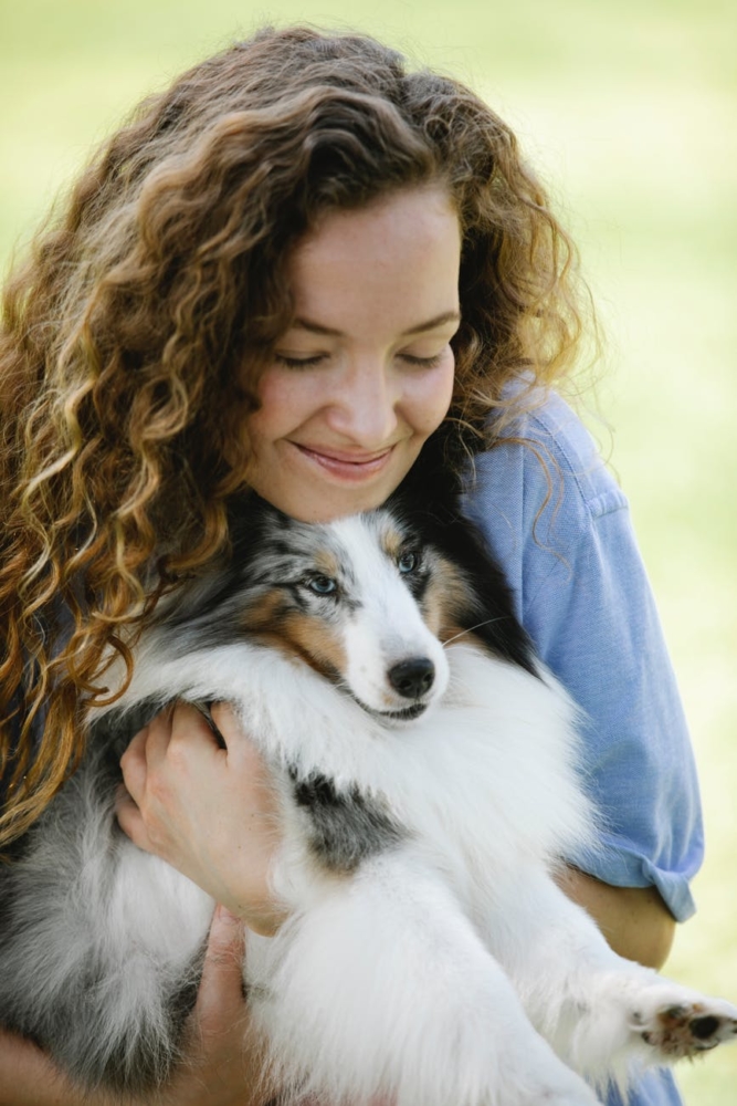 happy young woman holding fluffy dog