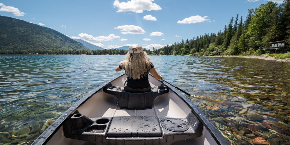 anonymous young lady paddling boat in lake during trip in mountains
